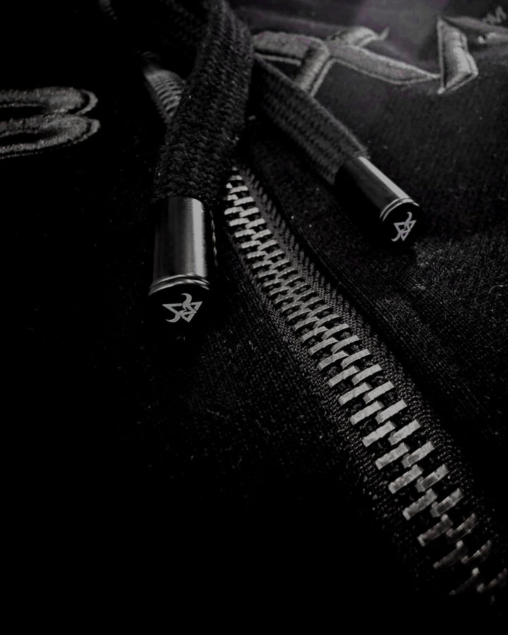 Close-up of black drawcords and silver zip hardware on the DBXA Ironveil hoodie.
