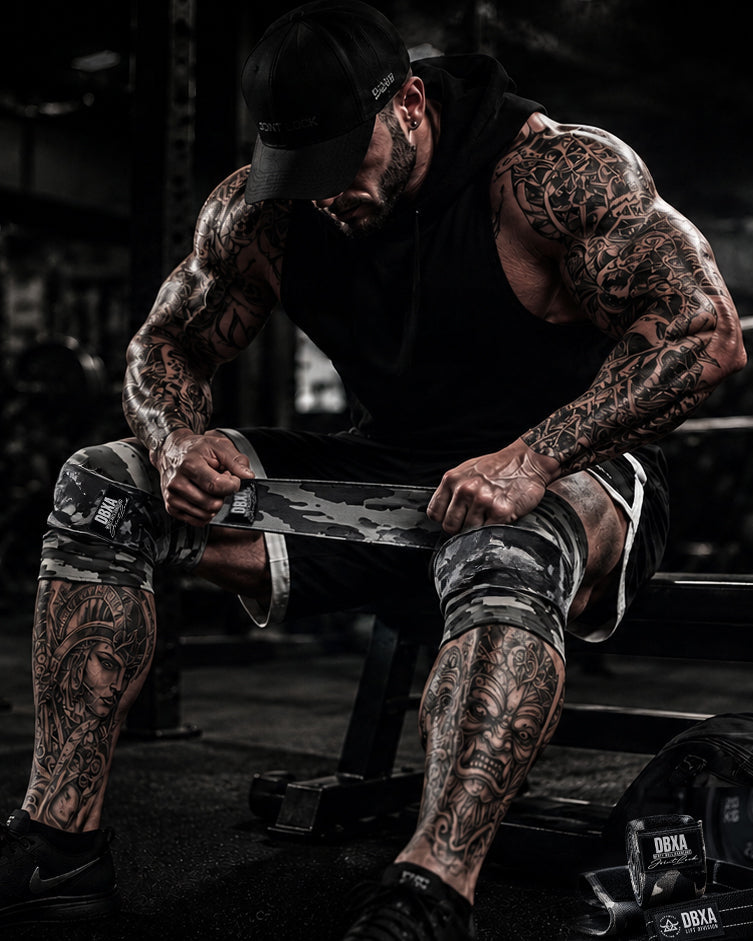 Man with tattoos sitting on a bench in a dark, industrial setting
