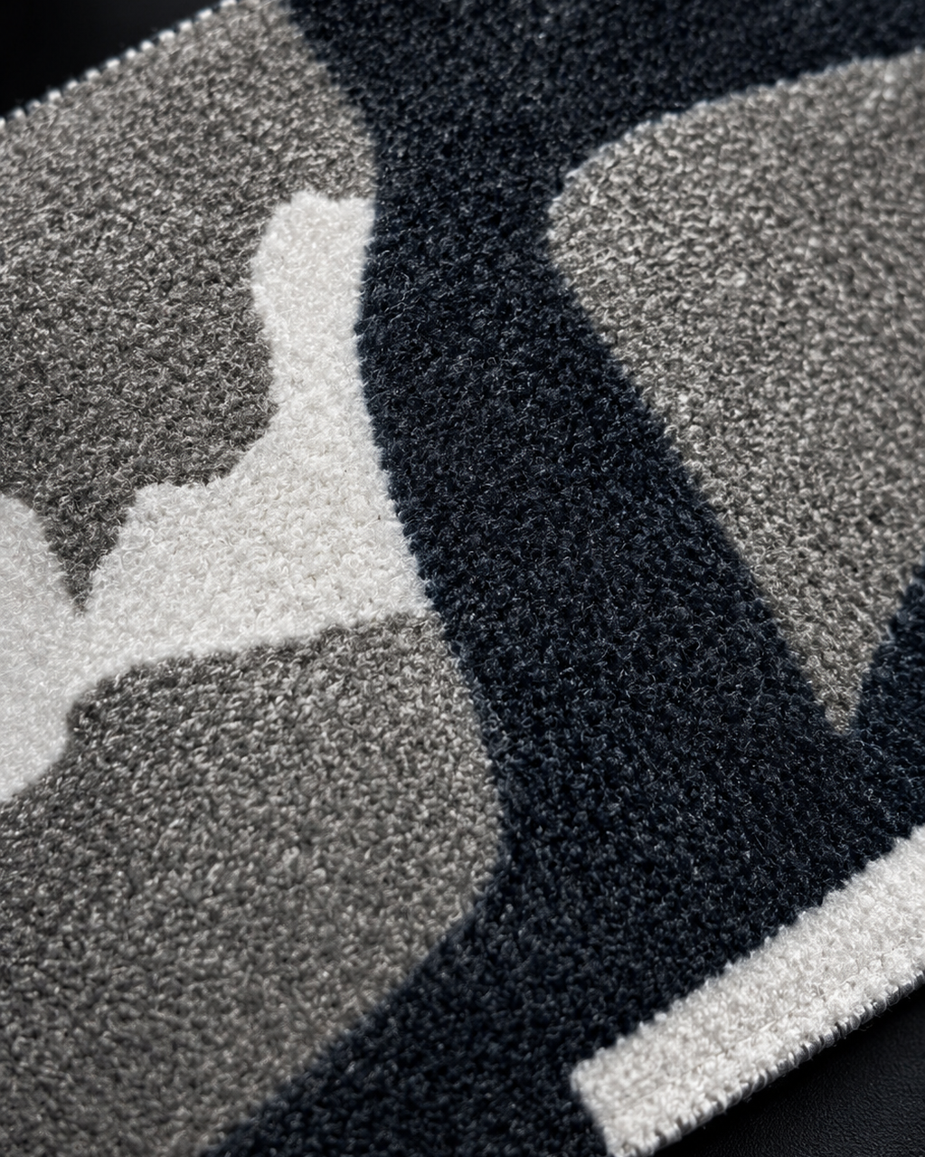 Close-up of a textured black and gray rug with geometric patterns.