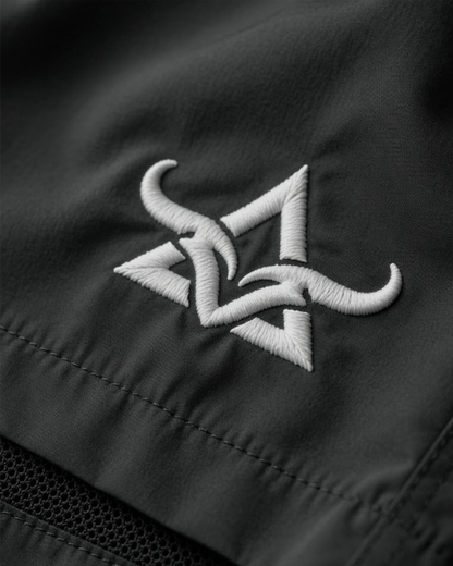 Close-up of a black shorts with a white embroidered logo on a dark background
