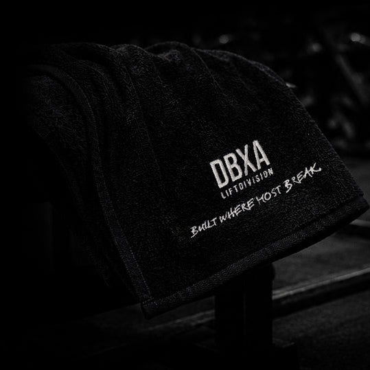 Black towel with 'DBXA' branding on a wooden surface