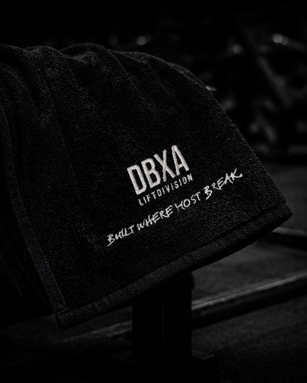 Black towel with 'DBXA' branding on a wooden surface