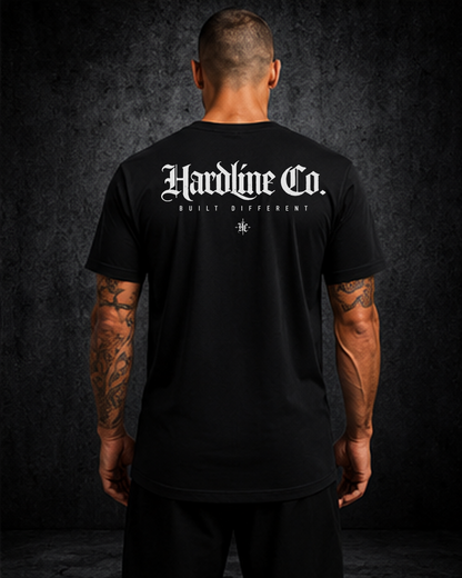 Person wearing a black t-shirt with 'Hardline Co.' logo on the back against a dark background