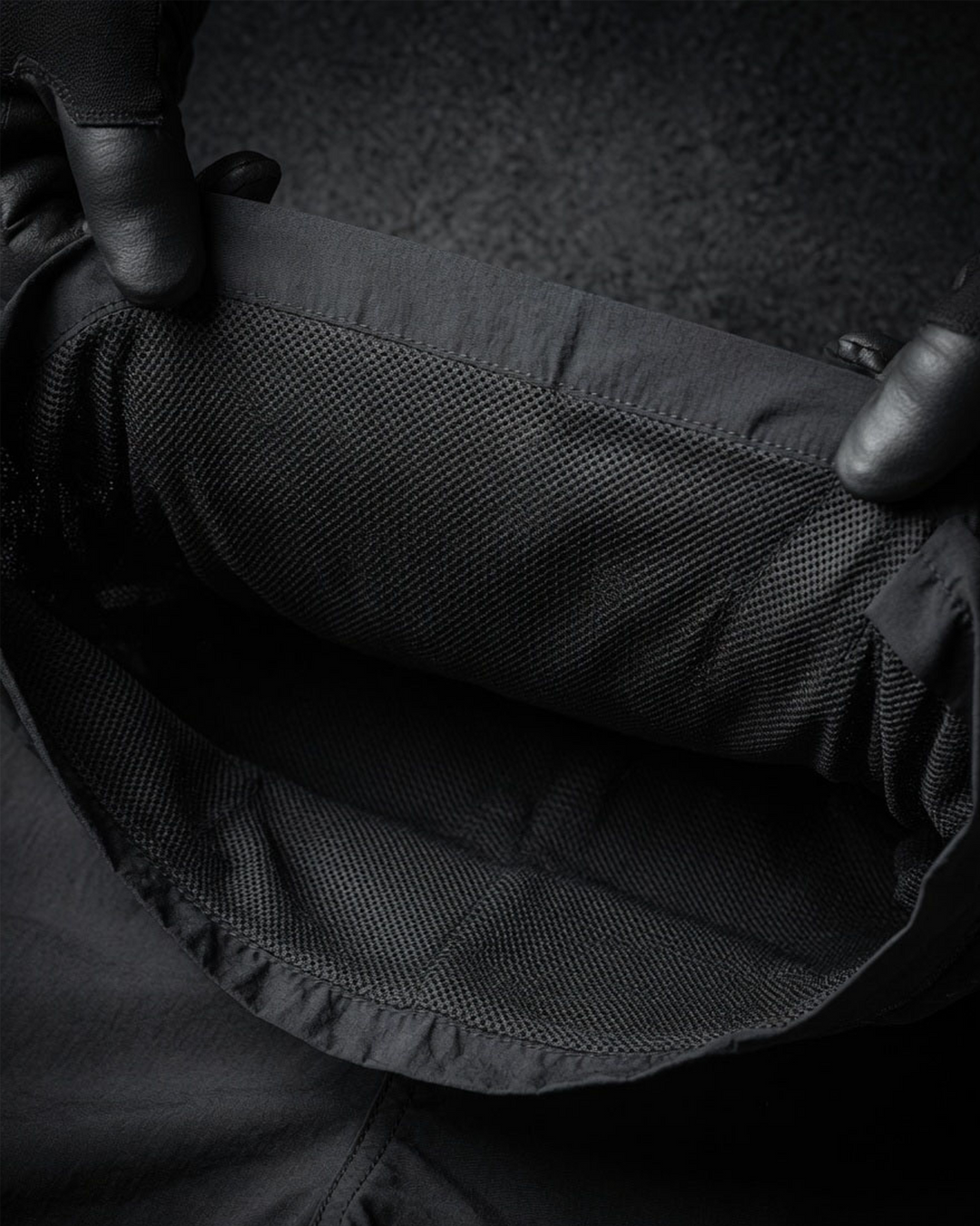 Close-up of a person holding a black shorts with a inner mesh lining.