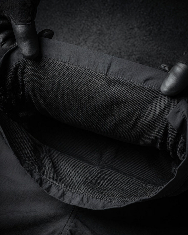 Close-up of a person holding a black shorts with a inner mesh lining.