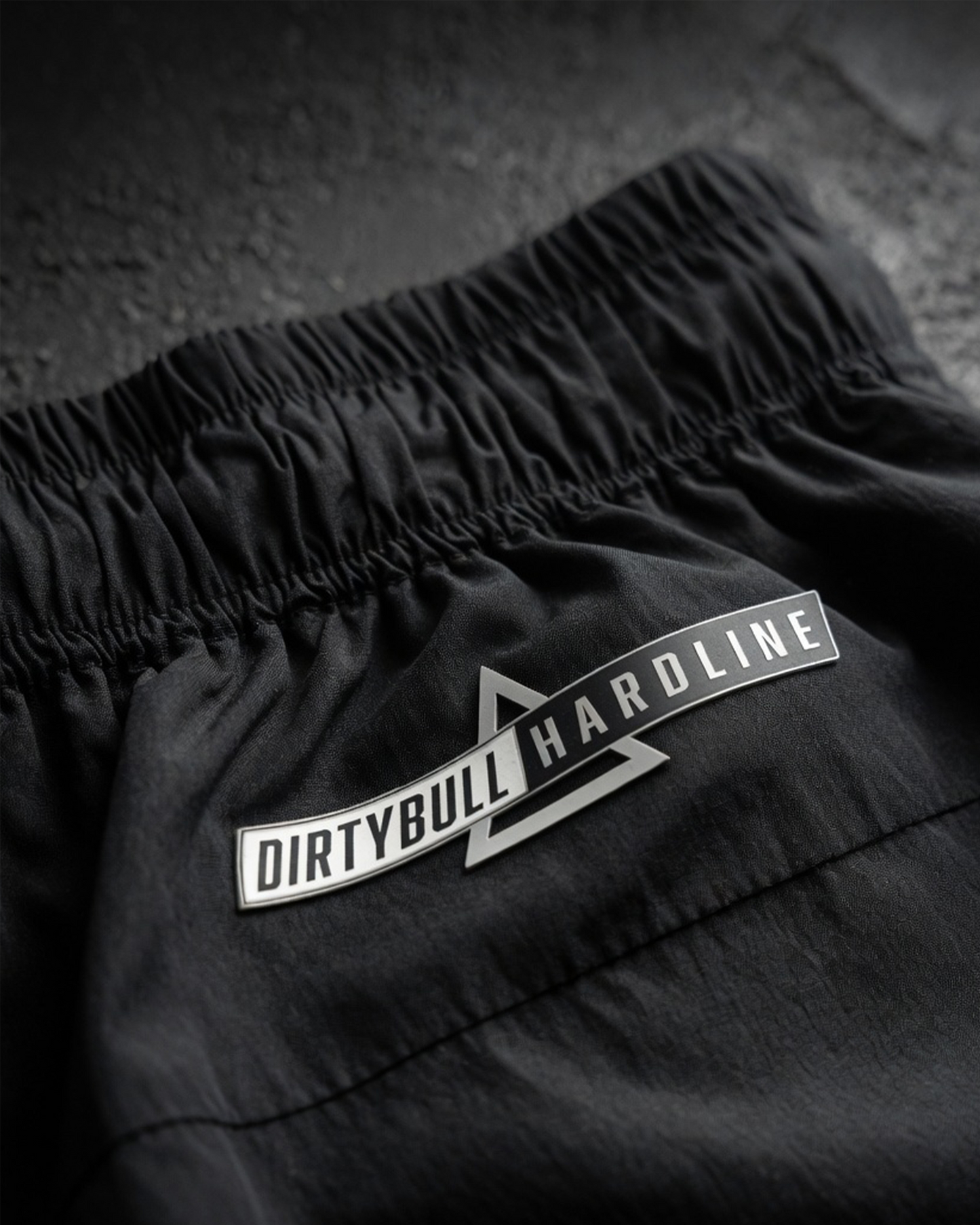 Black shorts with 'DIRTYBULL HARDLINE' logo on a textured surface