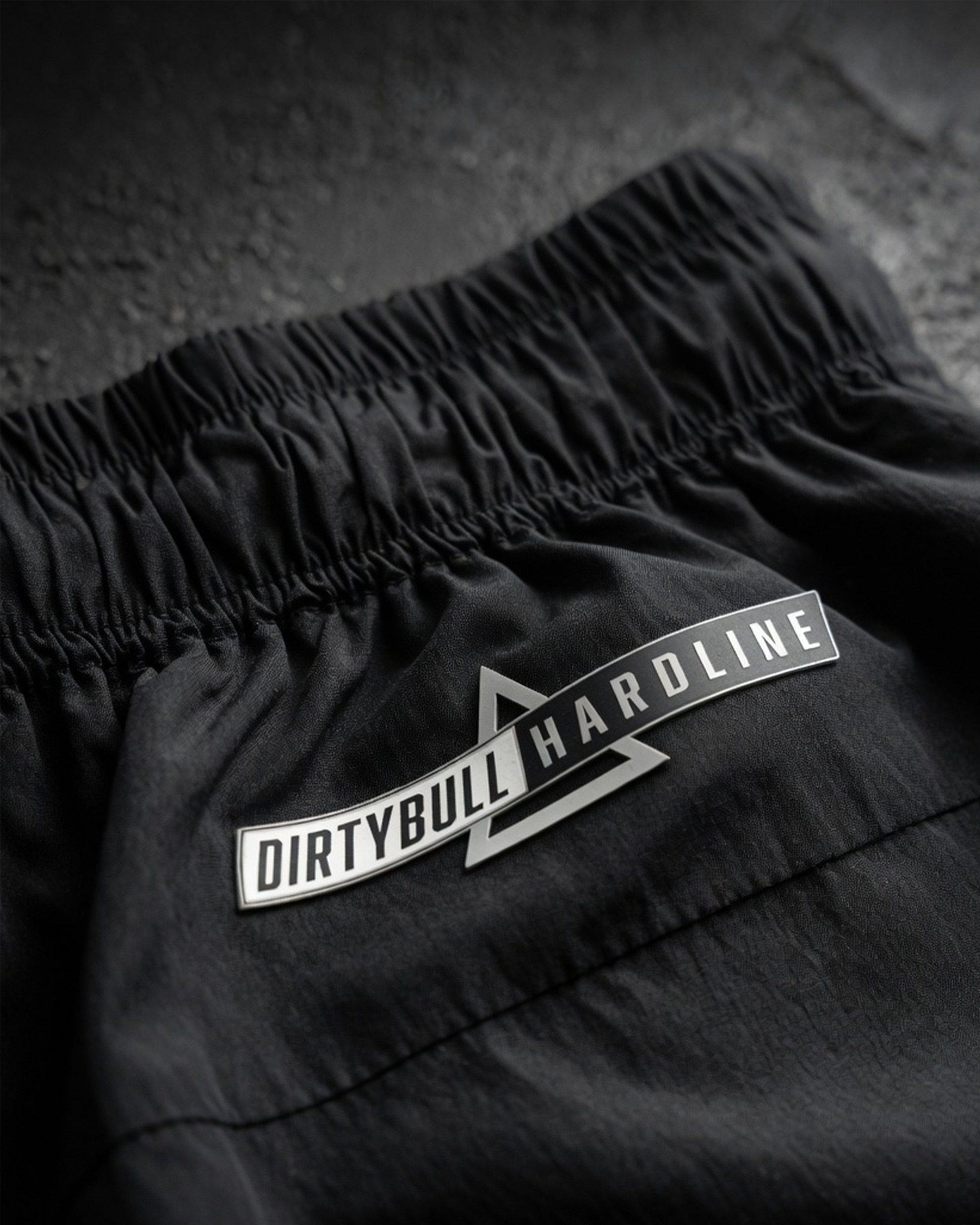 Black shorts with 'DIRTYBULL HARDLINE' logo on a textured surface