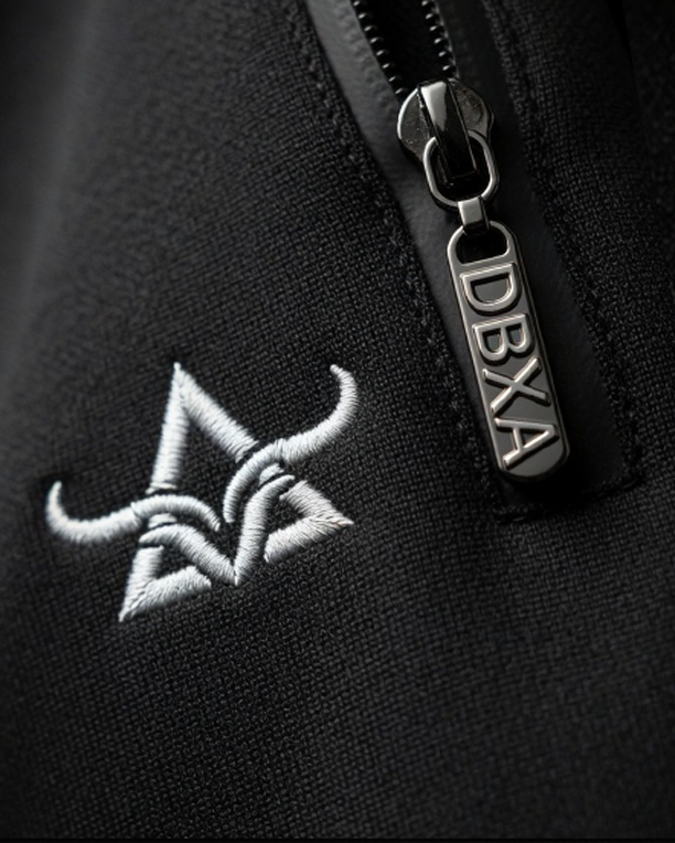 Close-up of the DBXA zipper pull and embroidered bull logo on Corestrike Pants