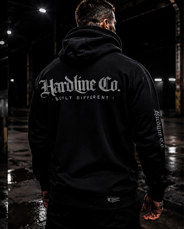 Man wearing a black Hardline Co. Hoodie showing the rear logo