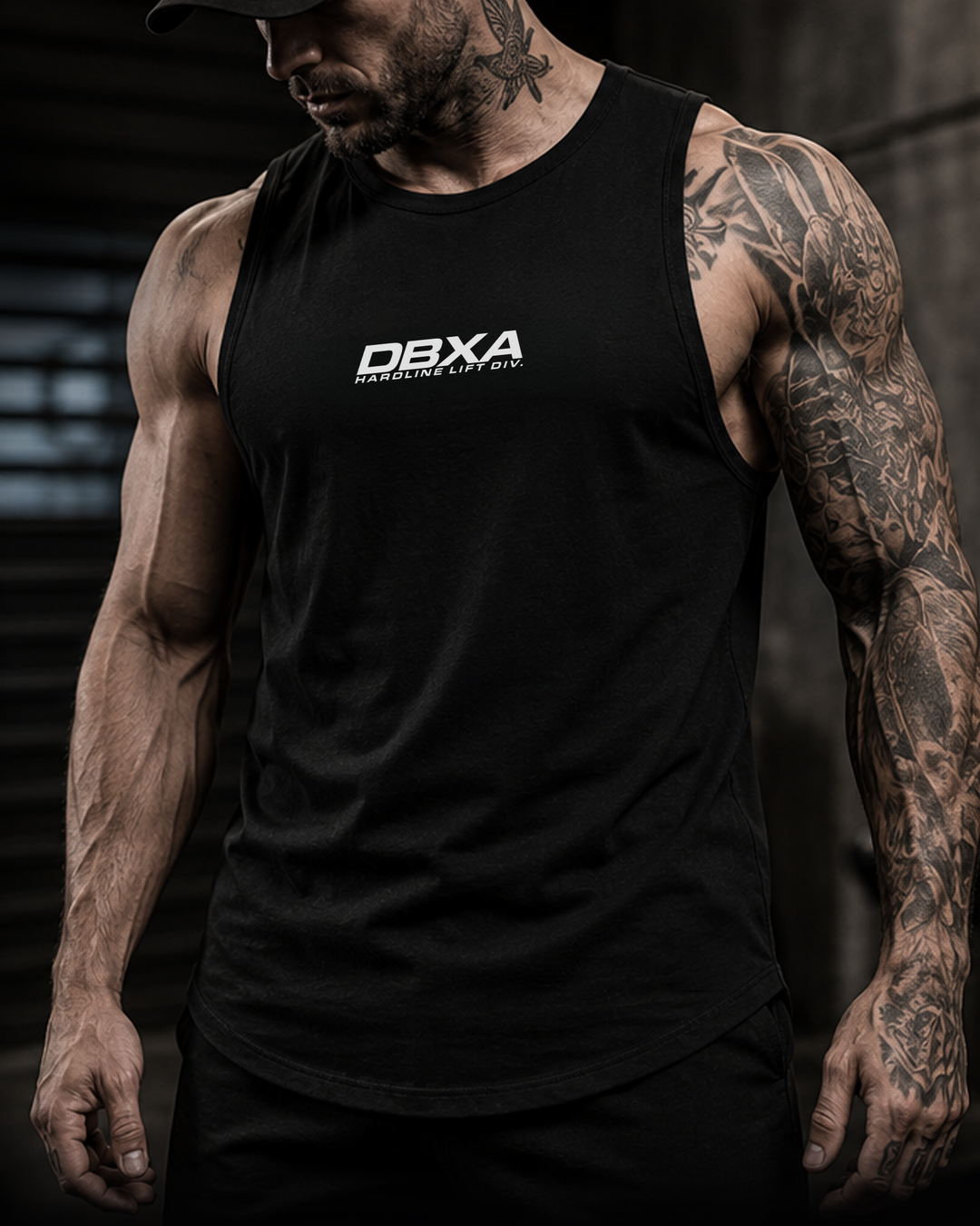 Man wearing a black tank top with DBXA logo against a dark background