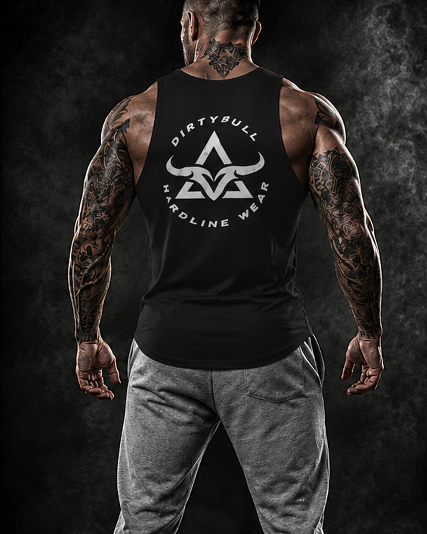 Man wearing a black tank top with 'Dirty Bull Hardline Wear' logo on a dark background