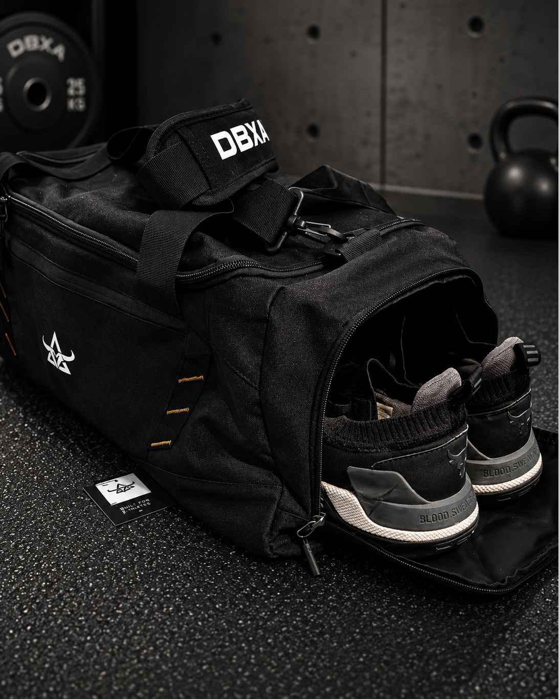 Black gym bag with DBX branding on a dark surface with shoes inside