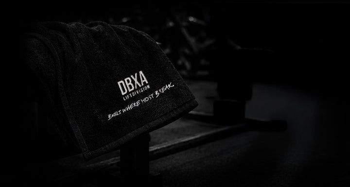 Black DBXA Lift Division gym towel draped over a training bench