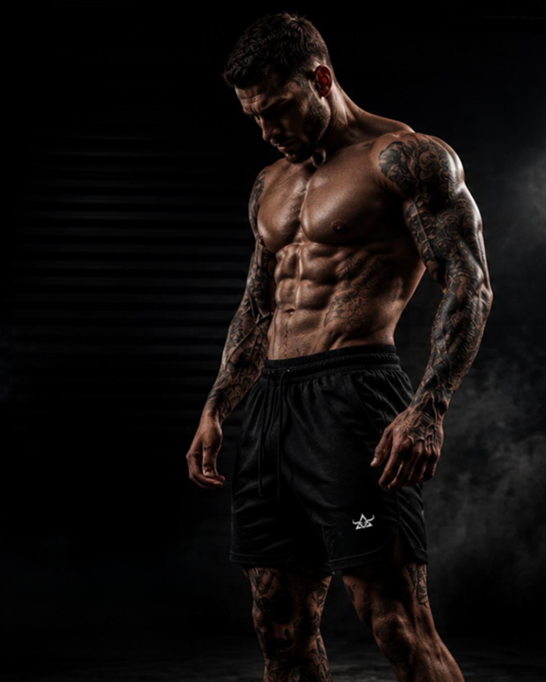 Male model wearing black DBXA Ironstrike Shorts in a dark gym setting.