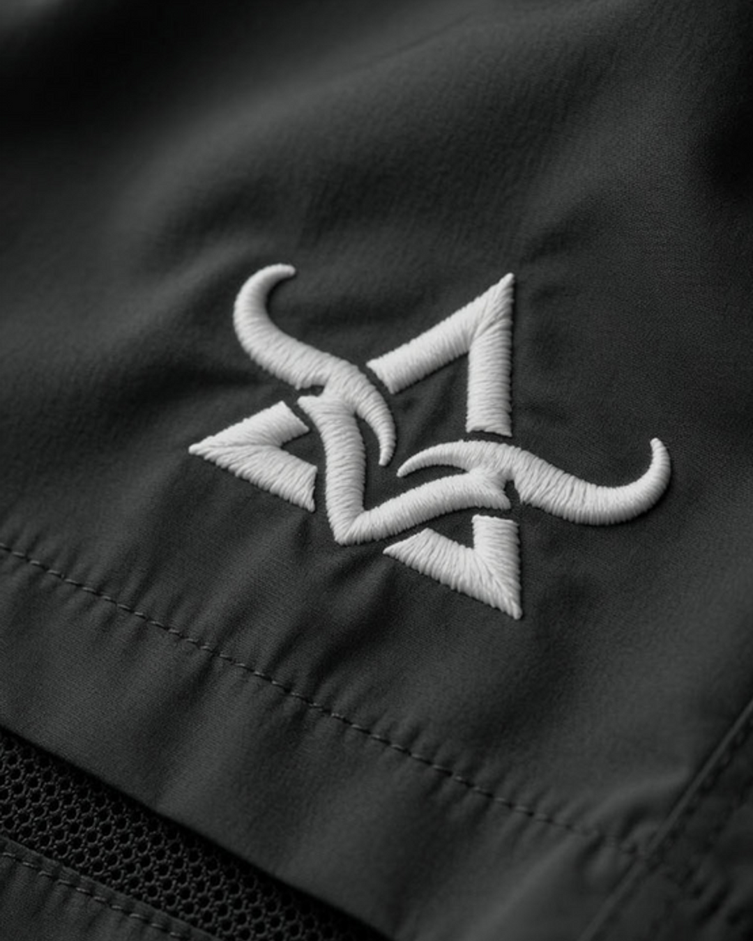 Close-up of embroidered DBXA branding on black Ironstrike Shorts.