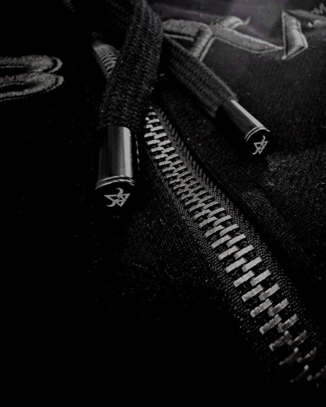 Close-up of black drawcords and silver zip hardware on the DBXA Ironveil hoodie.