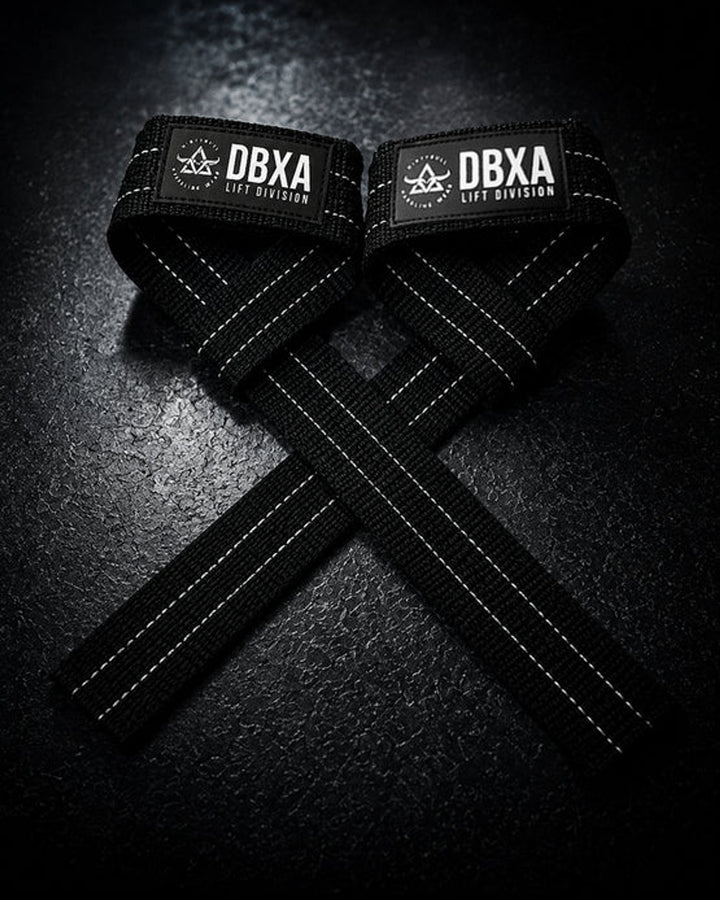 Black DBXA lifting straps crossed on a dark surface