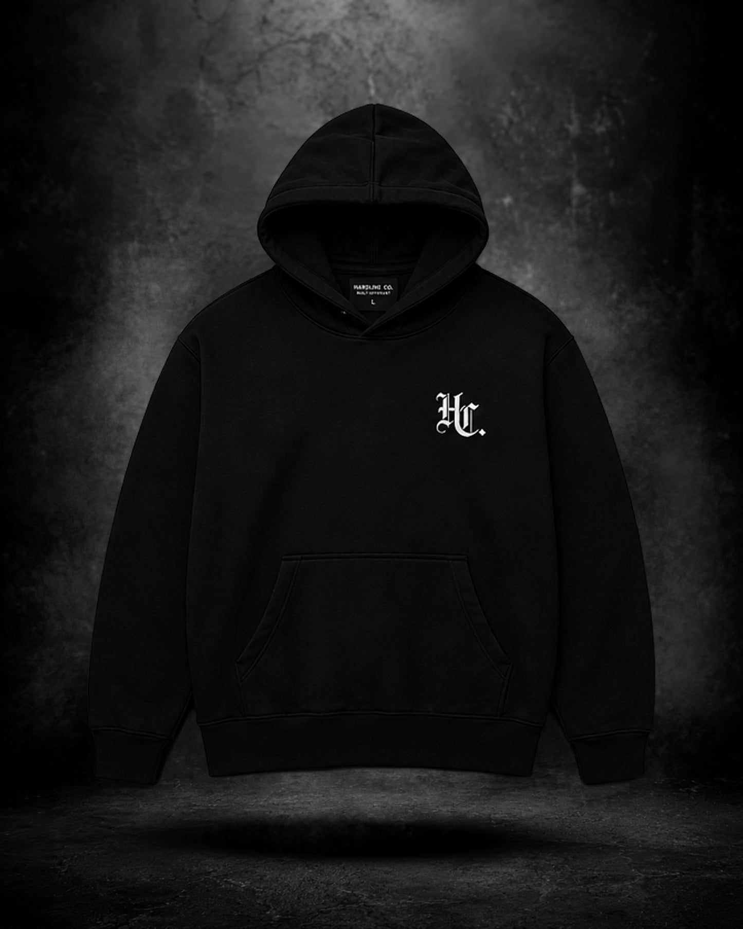 Black hoodie with a logo on the chest against a dark background