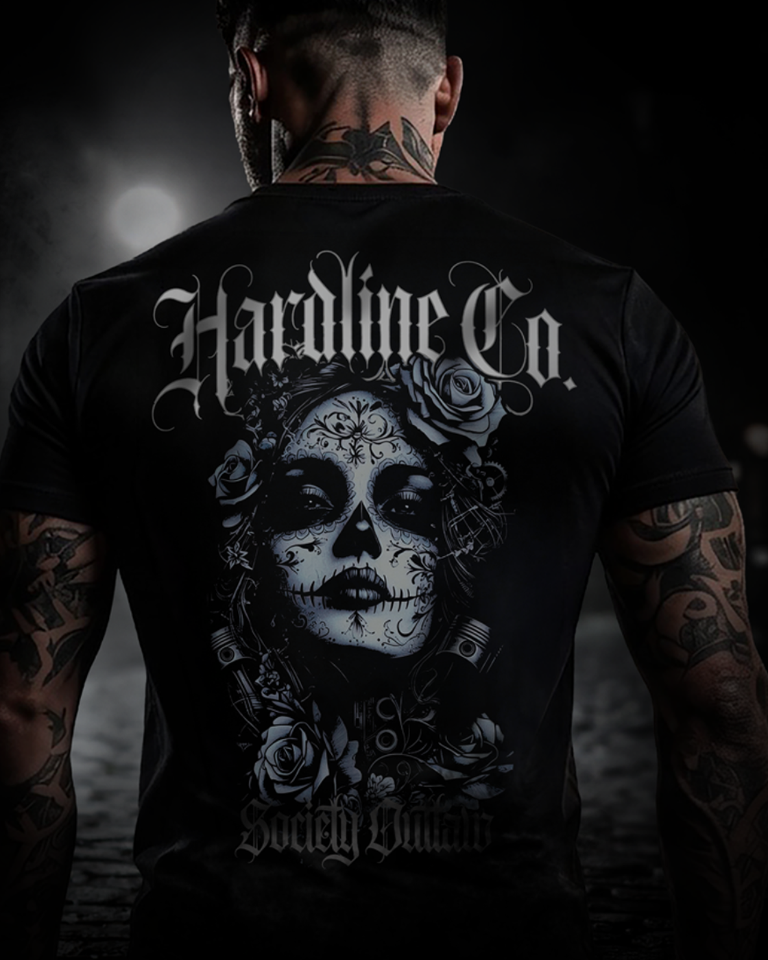 Person wearing a black t-shirt with a skull design and text on the back, standing in a dark setting.