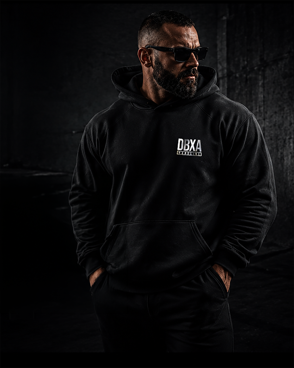 Man wearing a black hoodie with a logo on a dark background