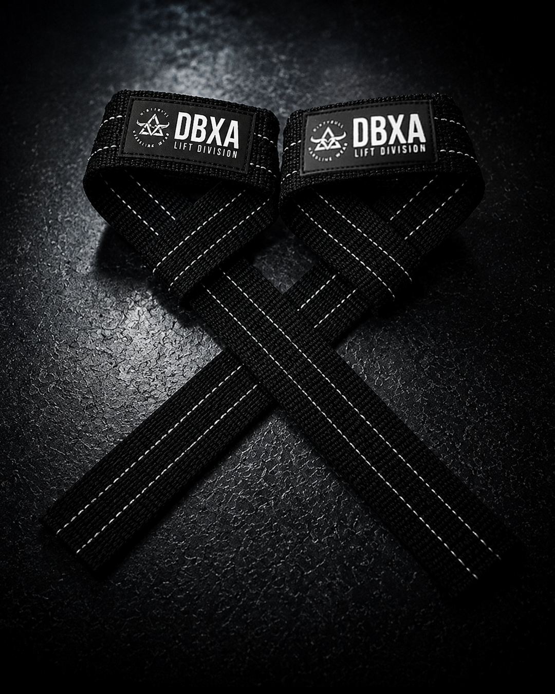 Black DBXA lifting straps crossed on a dark surface