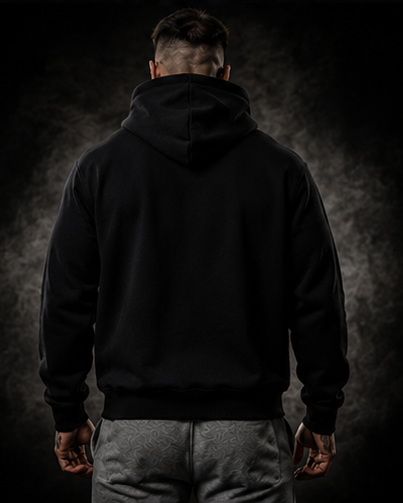 Person wearing a black hoodie and gray pants against a dark background