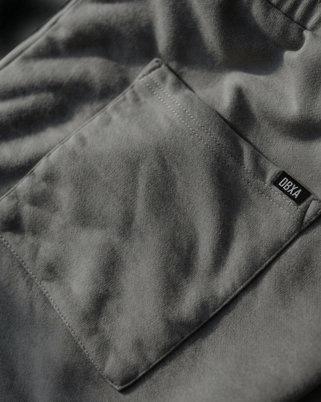 Close-up of a dark gray back of pants- right-rear-pocket. with a brand label on a blurred background