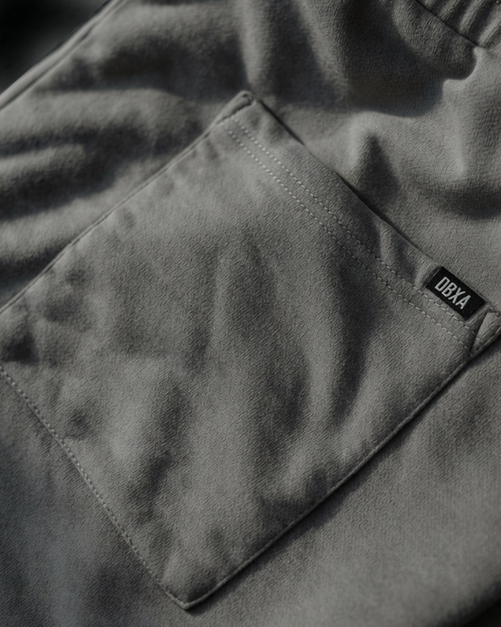 Close-up of a dark gray back of pants- right-rear-pocket. with a brand label on a blurred background