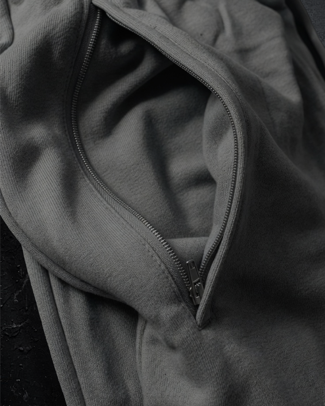 Close-up of a gray pair of pants-right pocket with a zipper detail on a dark background