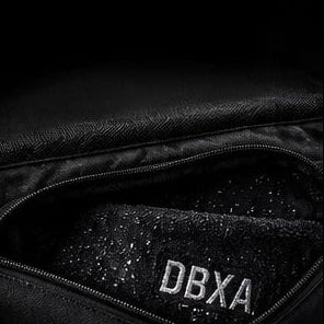 Close-up of a black jacket with 'DBXA' branding on a dark background