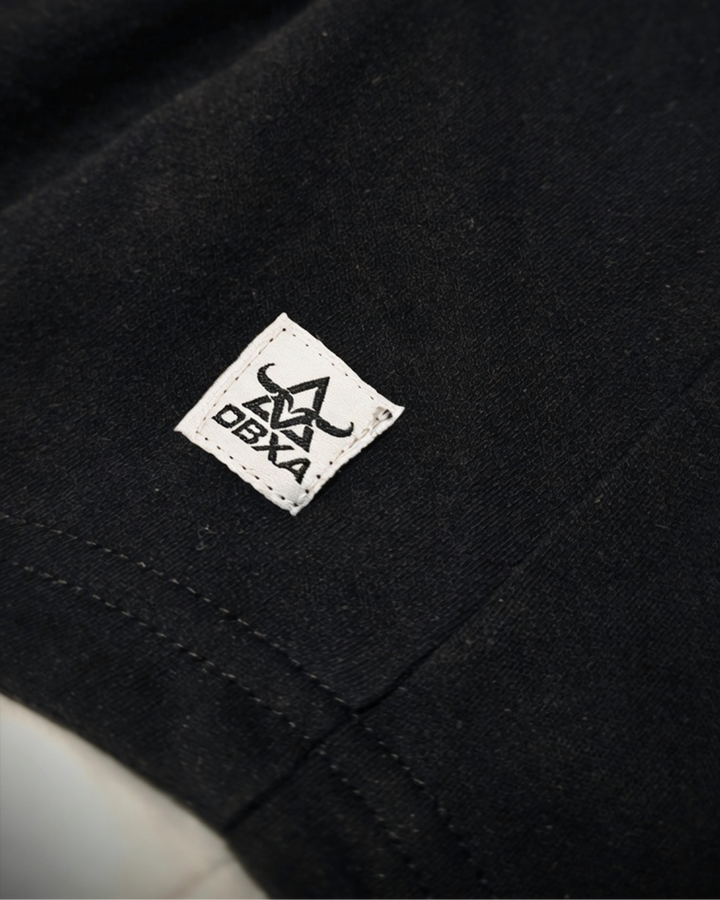 Close-up of the woven DBXA hem label on the Ironcore Hooded Tank